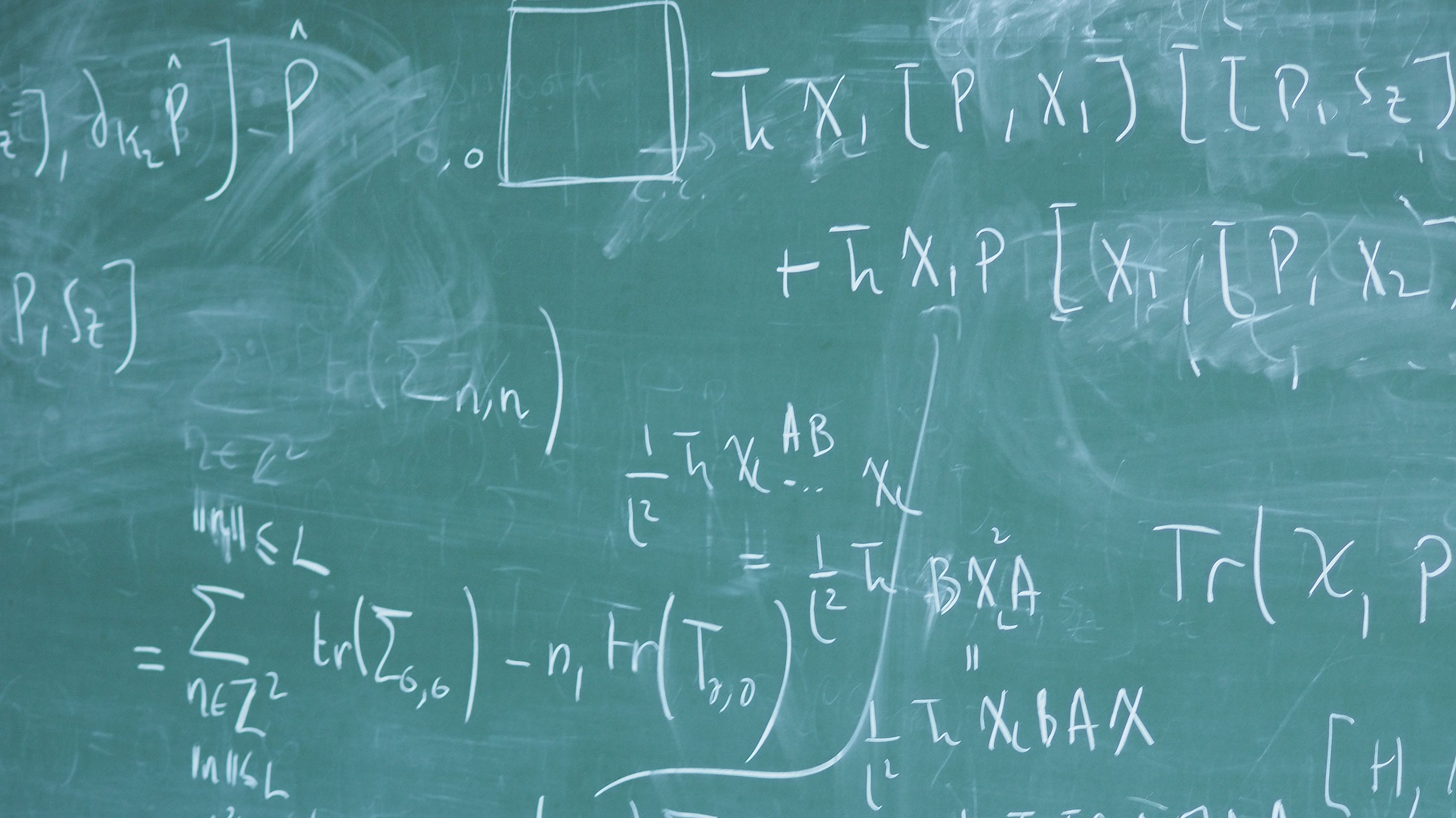 Dieses Bild zeigt einen Ausschnitt einer Tafel, auf der mit Kreide mathematische Formeln notiert wurden.